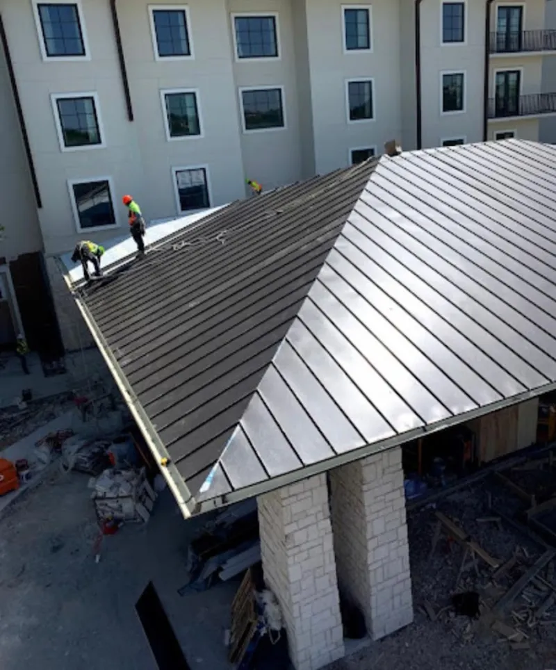 Crew installing standing seam metal roof panels on a commercial project in Blythewood